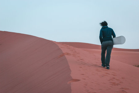 Boy makes sandboarding in the Sahara desert, Morocco. Safari desert camp in Merzougaの写真素材