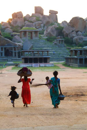 Hampi, India - October 7, 2011: Indian womans with kids walking in the bazaar street on the way to some very bad early in the morning at Hampi, Karnataka Estate, Indiaのeditorial素材