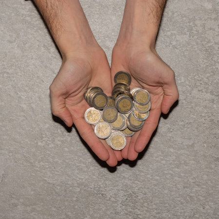 man hands holding a heap of euro coins background, top view.