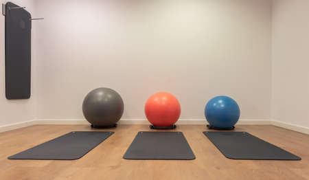 Gym for fitness exercises. Fitball and mat lie on the wooden floor. Fitness, sport, training, gym and lifestyle concept backgroundの写真素材
