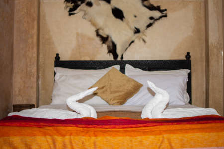 Two swans made of towels on bed in honeymoon suite colorful room hotel decorated for wedding or just married people.の写真素材