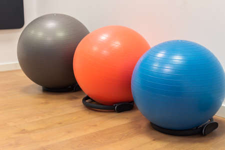 Fitness balls on wooden floor in the sport center. Exercise with gym balls. Gym for fitness exercises. Colorful fitness equipment on the floorの写真素材