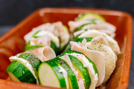Close up of a raw zucchini with turkey ham and black pepper on the top.の写真素材