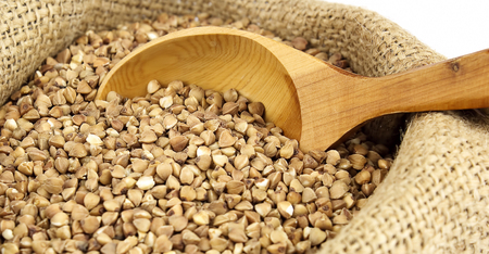 Buckwheat with wooden spoon in jute sack close upの写真素材