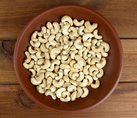 Raw cashew nuts in bowl on textured wooden background, table top viewの写真素材