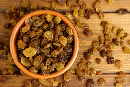 Raisins in bowl over wooden backgroundの写真素材