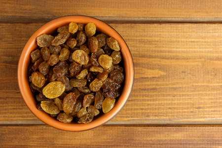 Raisins in bowl over wooden backgroundの写真素材