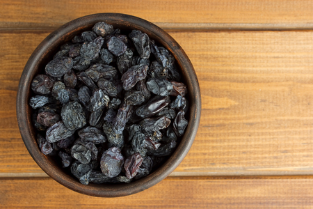Raisins in bowl over wooden backgroundの写真素材