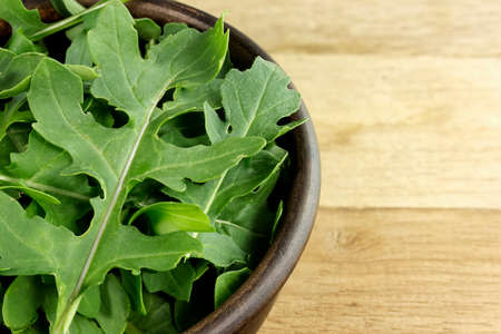 Fresh green arugula in bowl on wooden tableの写真素材