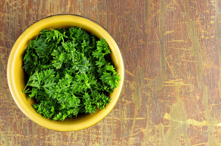 Top view of fresh parsley leaves in bowl on wood backgroundの写真素材