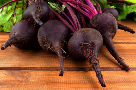 Organic red beets with green leaves on an old wooden table. Rustic style