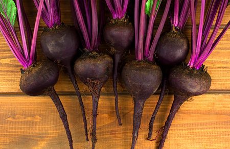 Organic red beets with green leaves on an old wooden table. Rustic style