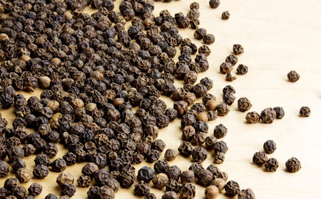Heap of hot black pepper on a wooden table
