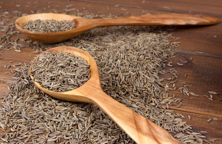 Cumin dry seeds  in wooden spoon on a wooden table. Cumin seeds in wooden spoon 