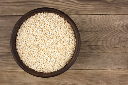 White sesame seeds in a bowl on wooden backgroundの写真素材