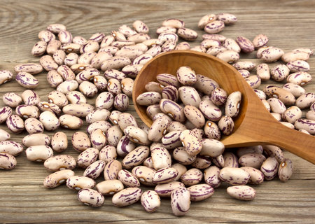 Haricot beans in a wooden spoon on white wooden background