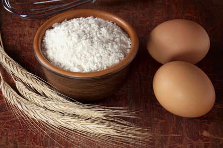 Baking background with white flour on rustic wooden table. Baker workplace with flour