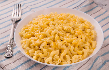Macaroni and cheese on a white plate on a gray background. American mac and cheese