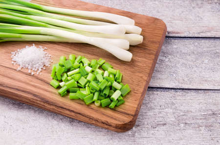 Spring onions also known as salad onions, green onions or scallions on wood backgroundの写真素材