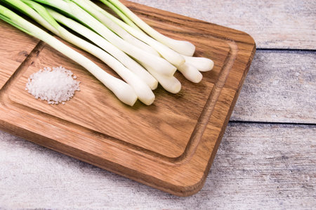 Spring onions also known as salad onions, green onions or scallions on wood background