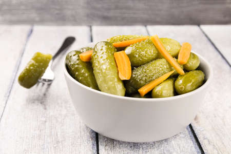 Pickled cucumbers gherkins with carrots on a wooden rustic table. Pickled cucumbers in a bowl.の写真素材