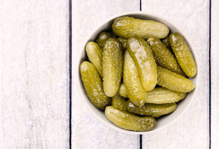 Pickled cucumbers gherkins on a wooden rustic table. Pickled cucumbers in a bowlの写真素材