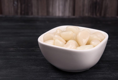 Tasty pickled young garlic in the bowl. Canned garlic.