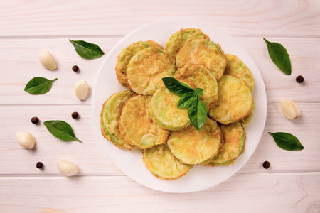 Baked zucchini with cheese, garlic and fresh herbs on a white wooden background. Delicious food.の写真素材