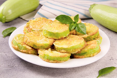 Baked zucchini with cheese, garlic and fresh herbs on a gray background. Delicious food.の写真素材