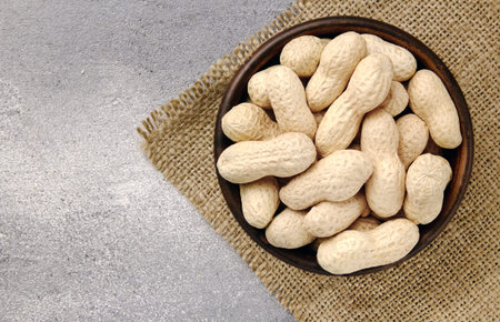 Raw Peanuts in a Bowl on gray table. Natural nutrition food.