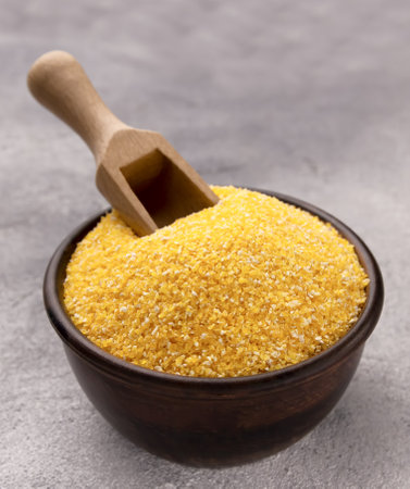 Raw cornmeal in bowl on a gray table, closeup. Space for textの写真素材
