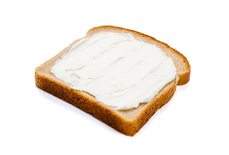 a slice of bread with fresh cream cheese on a white backgroundの写真素材