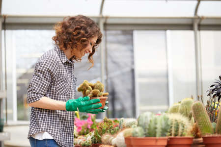 happy female nursery worker trimming plants in greenhouseの写真素材