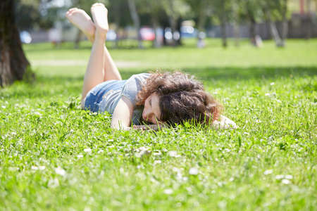Beautiful young woman lying on a field enjoying natureの写真素材