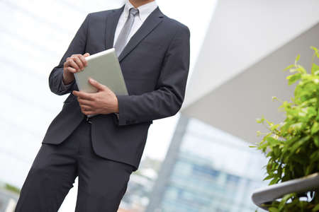 business man using tablet PC outside office buildingの写真素材