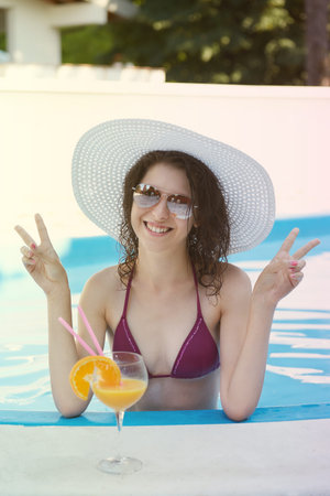 Happy smiling woman with straw hat in swimming pool