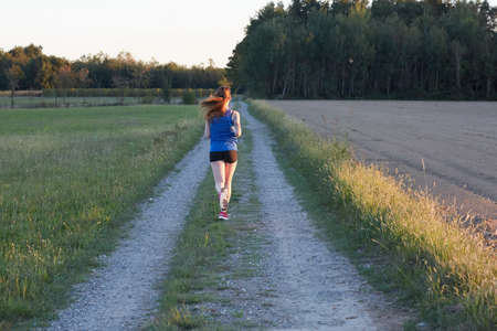 Fit woman running fast, training in bright sunshineの写真素材