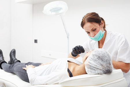 Cosmetologist applying permanent make up on lipsの写真素材