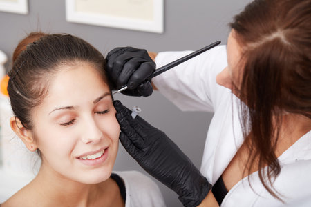 Cosmetologist applying permanent make up on eyebrows