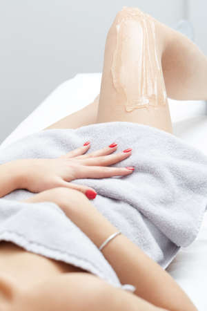 female beautician using laser machine on customer's leg at salonの写真素材