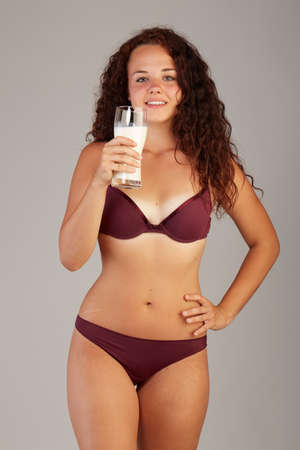 A woman is testing the skin on the thigh for the presence of stretch marks and drink milkの写真素材