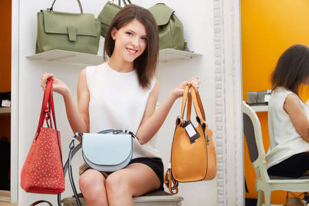 Woman trying bags and shoes sitting in a shopの写真素材