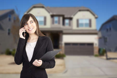 Woman real estate agent holding buy, sell and rent offers on residential house backgroundの写真素材