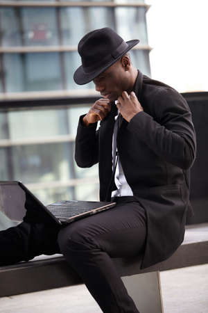 Portrait of young man sitting outside with laptopの写真素材
