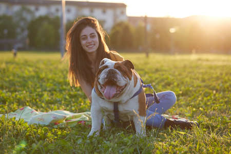 young Girl playing with English Bulldog at parkの写真素材