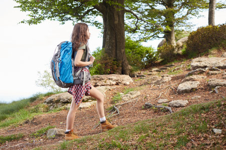 Traveling girl with backpack hiking in the mountains, eco tourism