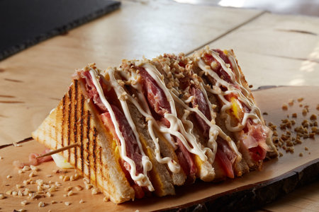 club sandwich made with tomato, cheddar, mayonnaise, chopped walnuts, ham on wooden trayの写真素材
