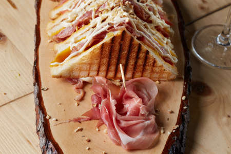 club sandwich made with tomato, cheddar, mayonnaise, chopped walnuts, ham on wooden trayの写真素材