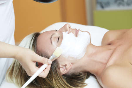 Beautiful young woman having a facial cosmetic mask at spa salonの写真素材