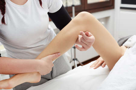 Therapist applying pressure on female legの写真素材